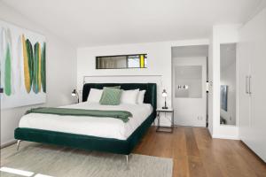 a bedroom with a large bed with a green headboard at Albertine House in Melbourne
