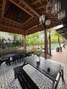 a patio with benches and a table and a pool at Koji Collection in Kerobokan