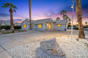 a house with palm trees in front of a driveway at The Perfect Getaway & Bunkhouse Casita with Heated Pool & Epic Game Room in Mesquite