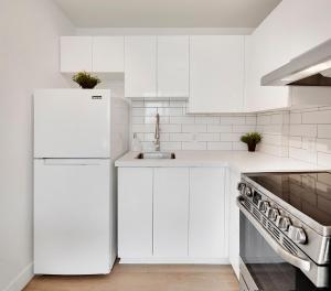 a white kitchen with a sink and a refrigerator at City Centre Studio - Best Location! in Vancouver +12 photos