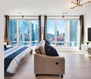 a bedroom with a bed and a chair and large windows at City Centre Studio - Best Location! in Vancouver