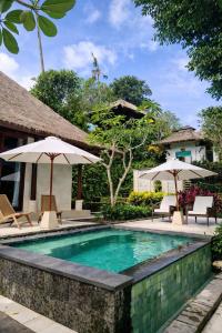 a swimming pool in a resort with umbrellas at VillaJewel Bali in Dalung
