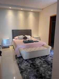 a bedroom with a bed with pink sheets and a rug at Lilly Queen I in Londrina