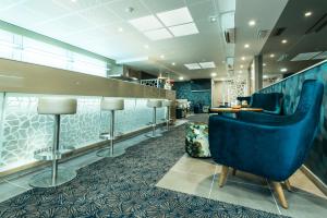 a lobby with a blue chair and a bar at Unique Hôtel & Spa in Saint-Raphaël