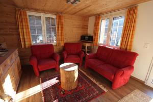 a living room with two red chairs and a table at Chalet Daheim in Reckingen - Gluringen