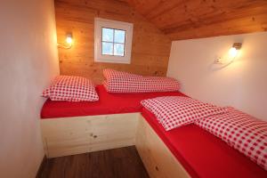 duas camas num pequeno quarto com lençóis vermelhos em Chalet Daheim em Reckingen - Gluringen