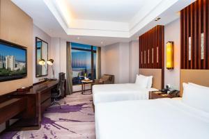 a hotel room with two beds and a television at Hotel Nikko Xiamen in Xiamen
