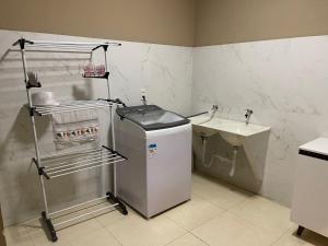 a small bathroom with a sink and a refrigerator at Lilly Queen I in Londrina +15 photos