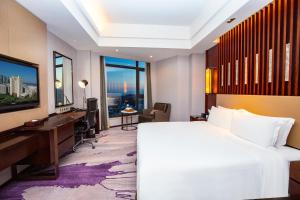 a hotel room with a bed and a desk and window at Hotel Nikko Xiamen in Xiamen