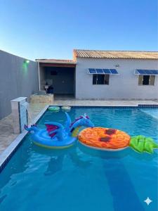 a swimming pool with two inflatables in the water at Casa Espaçosa com Piscina, 4 Quartos e Ar-Condicionado in Itanhaém