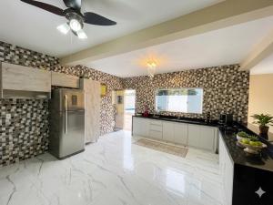 a kitchen with a ceiling fan and a refrigerator at Casa Espaçosa com Piscina, 4 Quartos e Ar-Condicionado in Itanhaém