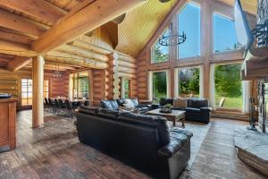 a living room with leather furniture in a log cabin at Fiddler Lake Resort - Moose 46 in Mille-Isles