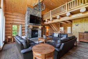 a living room with leather furniture and a stone fireplace at Fiddler Lake Resort - Moose 46 in Mille-Isles