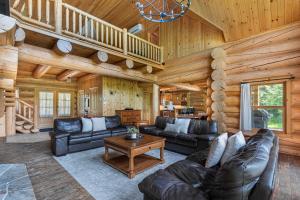 a living room with leather furniture in a log cabin at Fiddler Lake Resort - Moose 46 in Mille-Isles