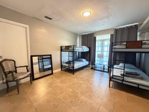 a room with three bunk beds and a chair at Bek's Hostel in Hallandale Beach