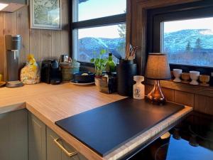a kitchen with a table with a lamp and a window at Original Trybo Cabin At Trysil Mountain in Trysil