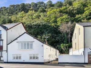 a white house and a building with trees in the background at Beach View Cottage Minehead in Minehead