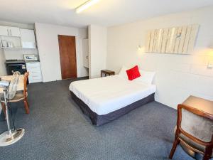 a bedroom with a bed with a red pillow on it at Midway Pacifica Lodge in Lower Hutt