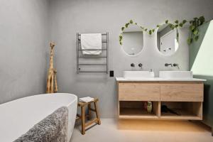 a bathroom with two sinks and two mirrors at The Reserve on Wooing Tree in Cromwell