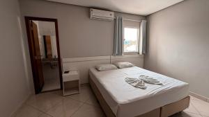 a small bedroom with a bed and a window at Hotel Estrela de Minas in São Gabriel