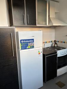 a kitchen with a white refrigerator and a stove at NM Apartamentos - LANUS OESTE in Villa Sarmiento