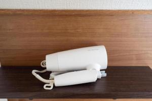 a white phone sitting on a wooden table at Biei Relax Stay B in Biei