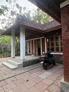 a motorcycle parked in front of a building at flamingos home stay in Padinjarathara