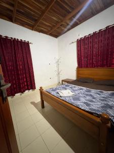 a bedroom with a bed with red curtains at flamingos home stay in Padinjarathara