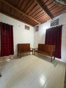 two benches sitting in a room with red curtains at flamingos home stay in Padinjarathara