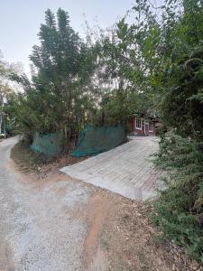 a dirt road next to a house with trees at flamingos home stay in Padinjarathara
