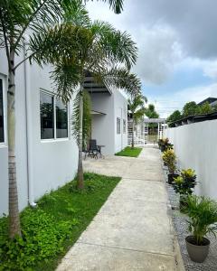 a sidewalk next to a white building with palm trees at Oasis House 1 in Cabuya