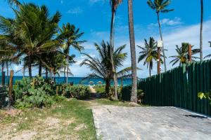 a path to the beach with palm trees and a fence at Beach Class Verano in Porto De Galinhas