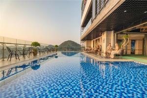 a hotel swimming pool with people sitting around it at Cat Ba Paradise Hotel - Sky Bar & Massage in Cat Ba