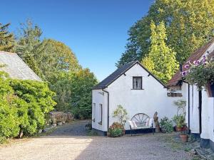 a white house with a chair in a driveway at Stables Cottage Ellicombe in Minehead