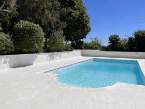 a swimming pool in a backyard with a wall and trees at Stables Cottage Ellicombe in Minehead