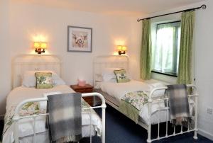 a bedroom with two beds and a window at Stables Cottage Ellicombe in Minehead