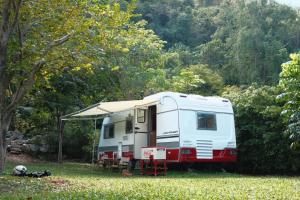 a white caravan parked in a field with a tent at The O' Khao Yai Mountain View Pool & Sauna Villa in Ban Tha Chang