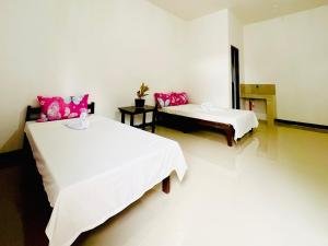 two beds in a room with pink pillows at ChicPoint Guesthouse in Sampong