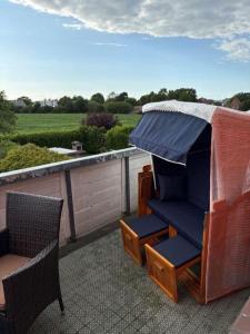 a patio with two chairs and an umbrella on a roof at Golfhues-Simone-Ferienwohnung-Suedbalkon in Wulfen auf Fehmarn