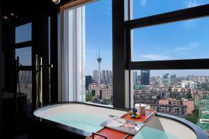 a bath tub in a room with a view of a city at SEYA Design Hotel - Chengdu Taikoo Li - Managed by SEYA GROUP in Chengdu