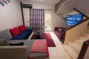 a living room with a couch and a tv at Cozy Townhouse with a Backyard in Sheikh Zayed