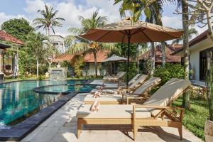an outdoor pool with lounge chairs and an umbrella at Rossa Garden Hotel Boutique in Candidasa