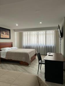 a hotel room with two beds and a desk at Hotel Altavista in Abancay
