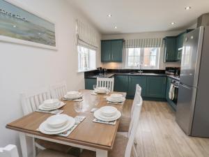 a kitchen with green cabinets and a wooden table with plates at Coastal Cottage in Reighton