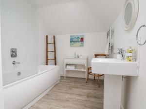 a white bathroom with a tub and a sink at Coastal Cottage in Reighton +28 photos