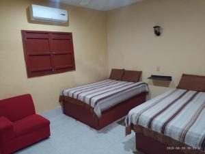 a bedroom with two beds and a red chair at Hotel Siglo XXI in Dzidzantún
