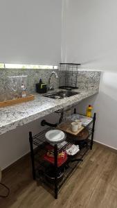a kitchen with a counter and a sink and a table at Vinhedo Villarejo - Chalés do Vinhedo in Paty do Alferes