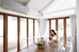 a woman sitting at a table in a room with windows at Unique Lanna Style Spa Pool Villa in Chiang Mai