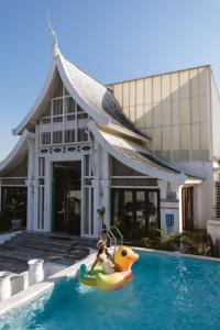a toy duck in a swimming pool in front of a house at Unique Lanna Style Spa Pool Villa in Chiang Mai