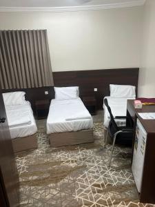 a hotel room with two beds and a desk at فندق جاردنز أوف كومفورت in Az Zahrāʼ